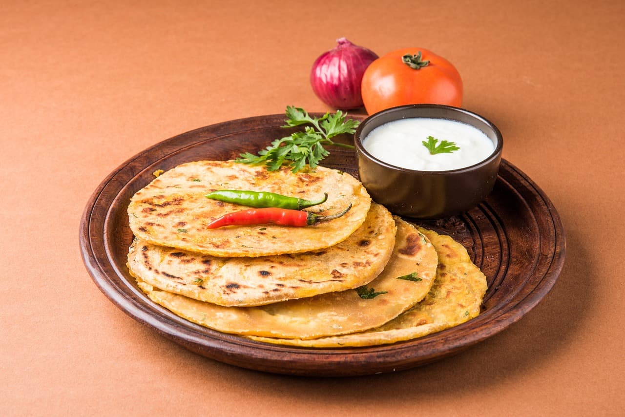 A stack of parathas with yoghurt and green chillies